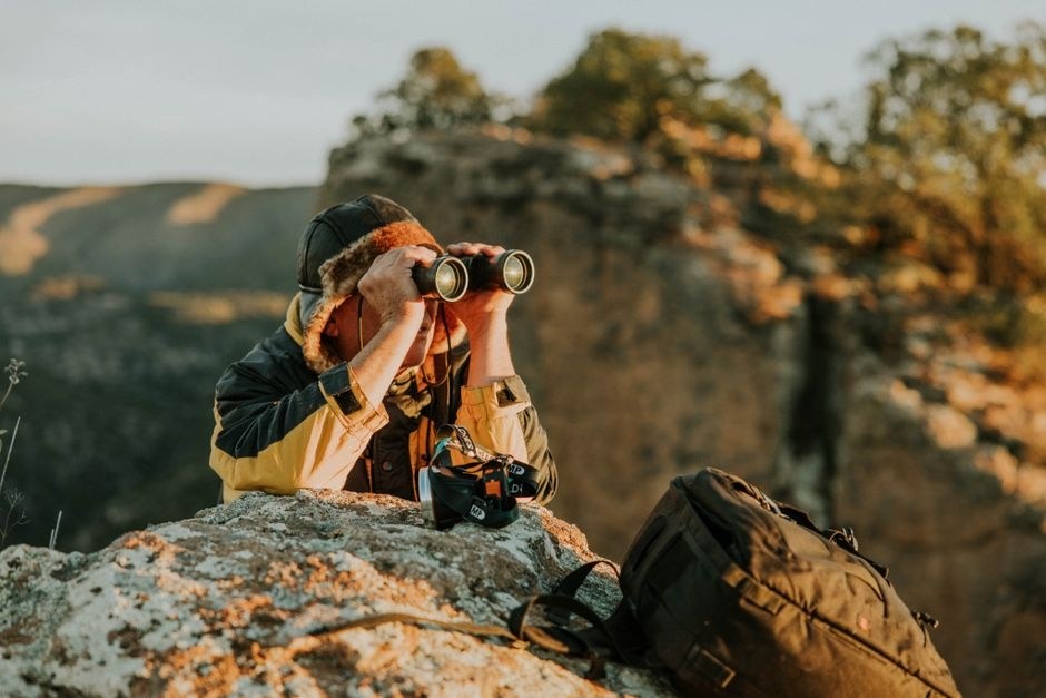 A photographer looking through a camera in a mountain landscape